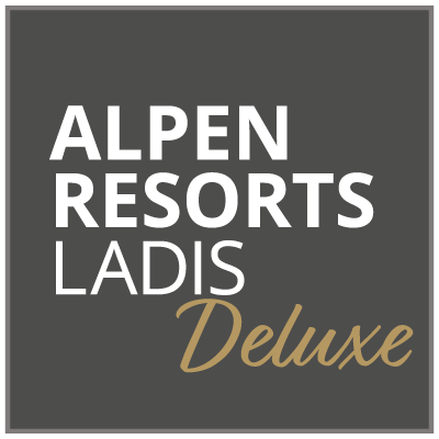 Logo mit dunkelgrauem Hintergrund und dem Text „ALPEN RESORTS LADIS“ in fetten weißen Buchstaben. Das Wort „Deluxe“ ist darunter in kursiver Goldschrift geschrieben.