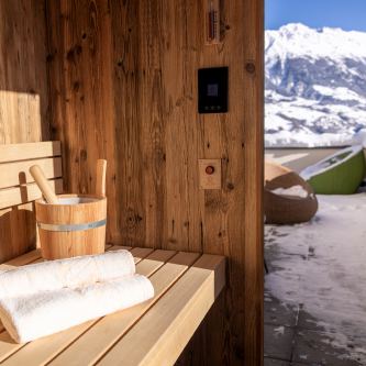 Erleben Sie ultimative Entspannung in einer gemütlichen Holzsauna, Teil eines Luxusapartments für 6-8 Personen in Serfaus-Fiss-Ladis. Genießen Sie den Blick auf die schneebedeckten Berge von der modernen Terrasse, wo ein Korbstuhl unter klarem blauen Himmel auf Sie wartet.