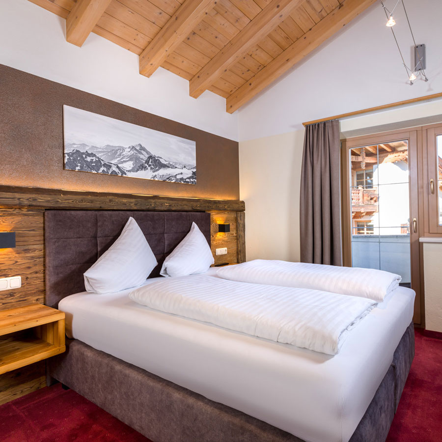 Dieses gemütliche Schlafzimmer ist Teil von Apartment 3, ideal für 2-3 Personen in Ladis. Es verfügt über eine Holzdecke, ein großes Bett mit weißer Bettwäsche und braunem Kopfteil sowie ein Landschaftsgemälde über dem Bett. Ein Fenster daneben öffnet sich zu einem bezaubernden Blick auf den Holzbalkon.