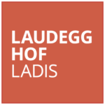 Rotes Quadrat mit weißem Text „Laudegg Hof Ladis“, der die Essenz von Urlaub in Ladis einfängt.