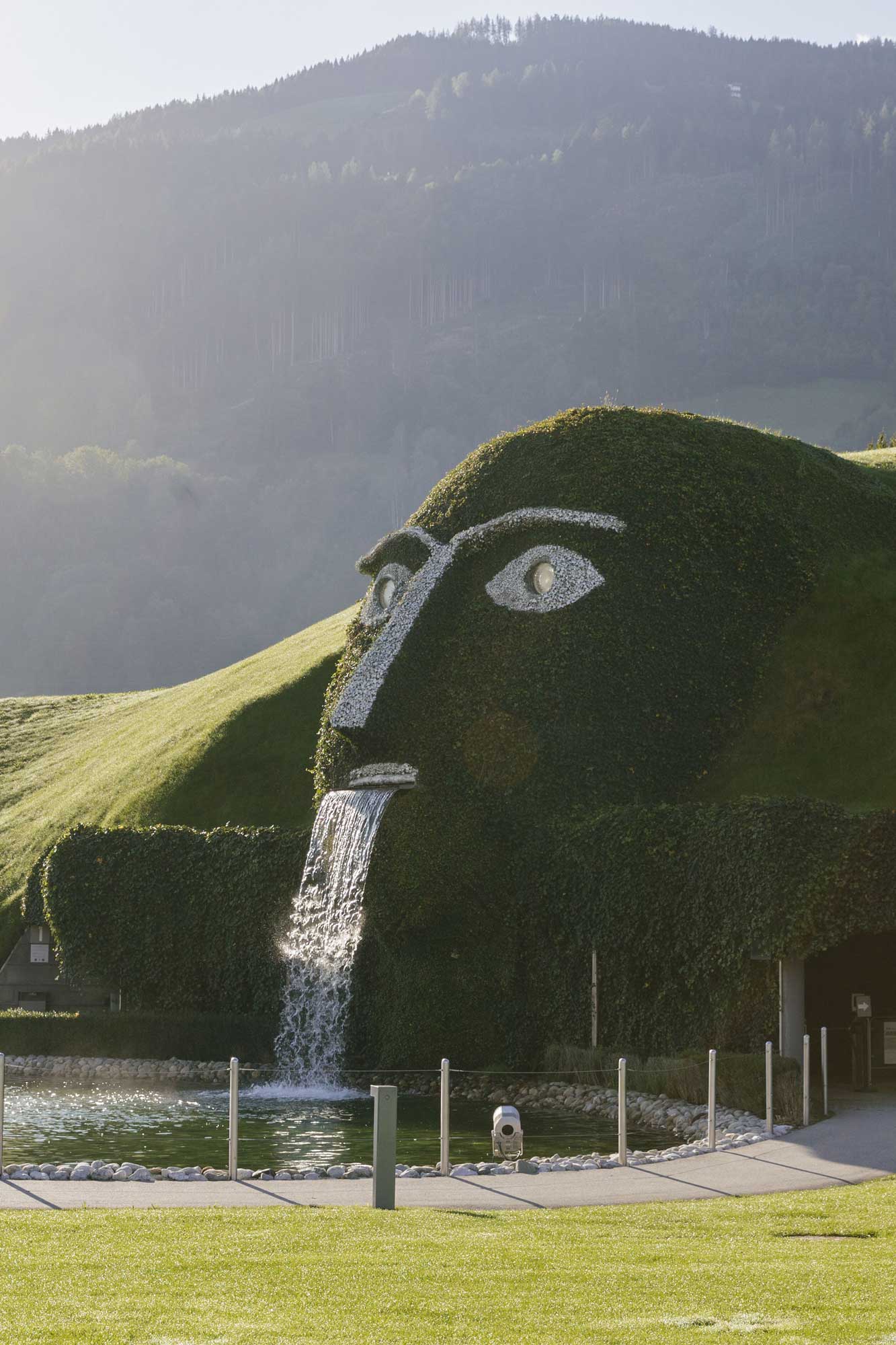Ein grasbewachsener Hügel in Form eines Gesichts mit einem Wasserfall, perfekt für den Sommerurlaub in Serfaus-Fiss-Ladis.