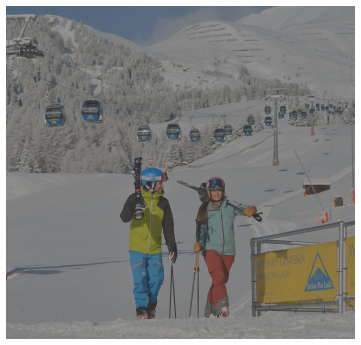 Zwei Skifahrer gehen auf verschneiten Pisten in der Nähe von Alpenresorts, mit Gondeln und Bergen im Hintergrund.