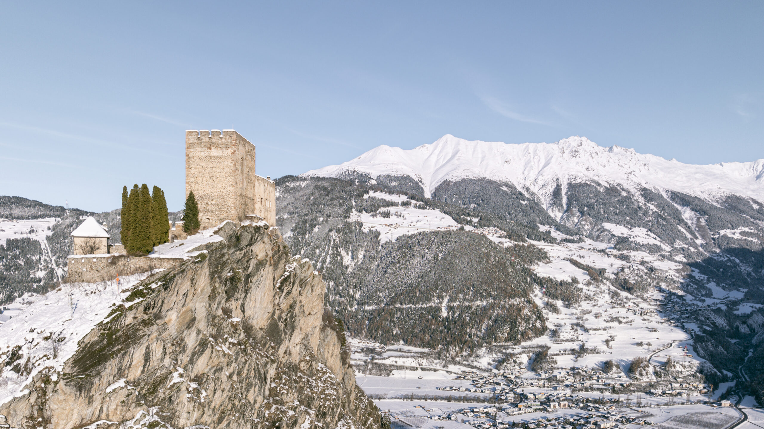 Ein Schloss auf einem schneebedeckten Felsen, Berge und ein Dorf - perfekt für Urlaub in Ladis.