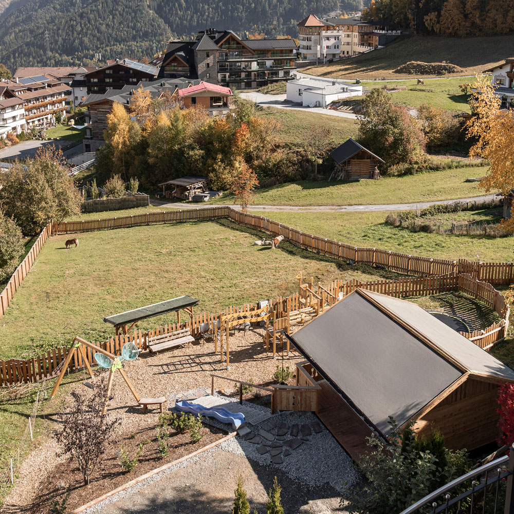 Ein Bergdorf mit eingezäunten Grasflächen in der Nähe von Mimis Kinderspielwelt im Alpenapart in Ladis.